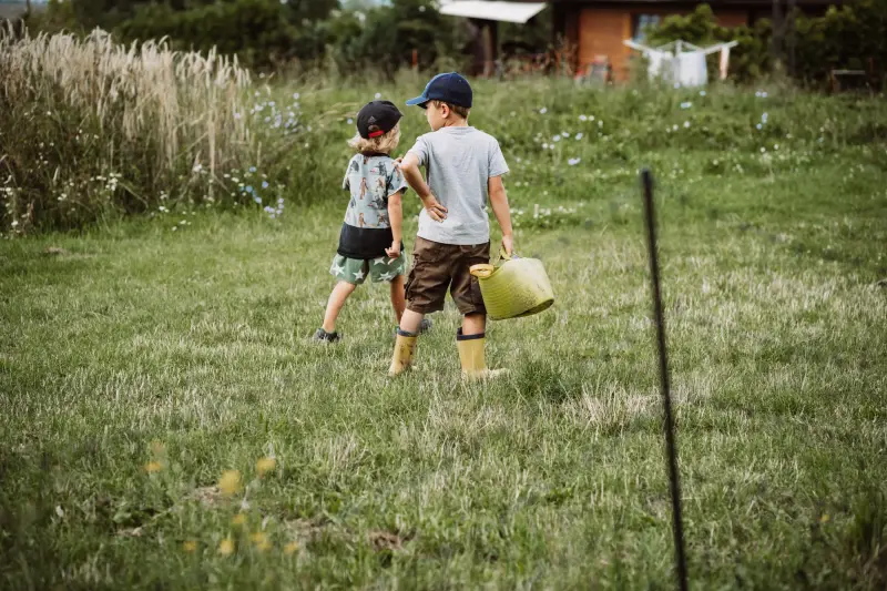 Zwei Kinder laufen mit einer Gießkanne über die Wiese