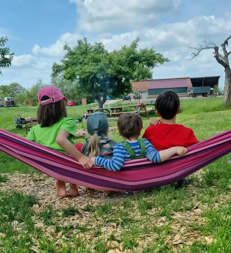 Vier Kinder sitzen zusammen in einer Hängematte