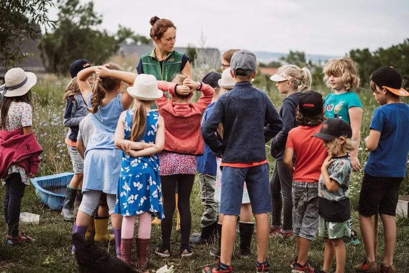 Marie Scharf mit einer Kindergruppe im Kreis auf dem Hof